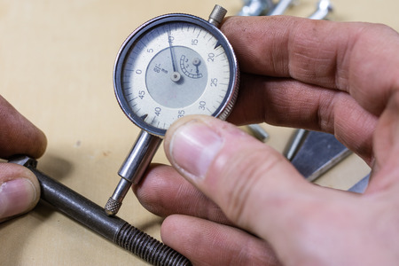 Tools and measuring accessories on a wooden workshop table. Making control measurements using calipers, micrometers and other measuring tools. Black background.の写真素材