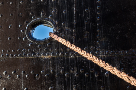 Mooring rope of a large ship standing in the port. Harbor cape wrapped with a mooring rope. Season...