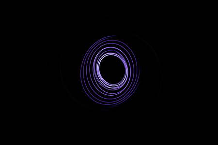 Painting with light coming from the diode. A spiral outline drawn by a flashlight suspended on a string. Black background.の写真素材