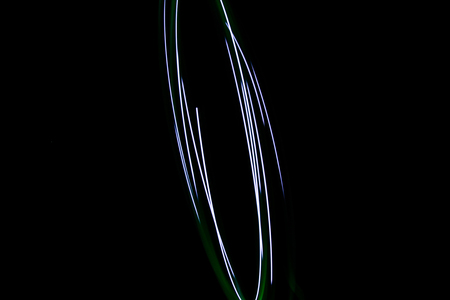 Painting with light coming from the diode. A spiral outline drawn by a flashlight suspended on a string. Black background.の写真素材