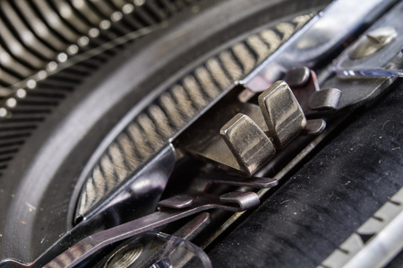 Typewriter shown in macro technology. A mechanical device for printing text. Light background.