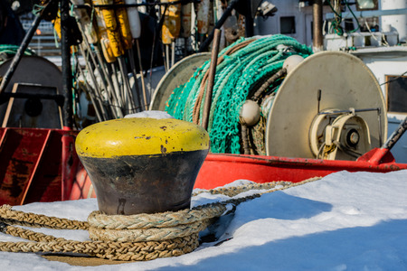 Fishing boats in the Polish fishing port on the Baltic. Fishing accessories, nets and ropes on a boat for fishing. Winter season.の写真素材