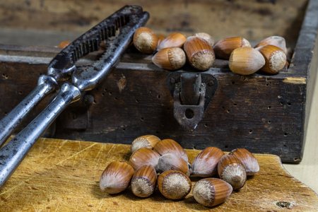 Tasty hazelnuts on a wooden kitchen table. Forest specialties and kitchen accessories. Dark...
