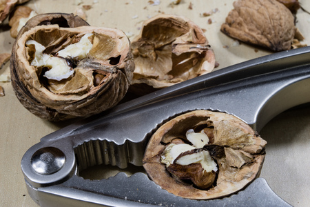 Walnuts on a wooden kitchen table. Nuts and a black wooden crate with a nutcracker. Black...