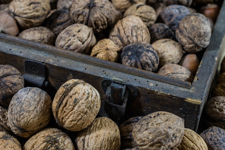 Walnuts on a wooden kitchen table. Nuts and a black wooden crate with a nutcracker. Black background.の写真素材