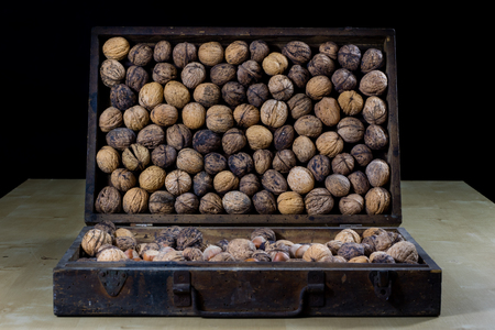 Walnuts on a wooden kitchen table. Nuts and a black wooden crate with a nutcracker. Black...