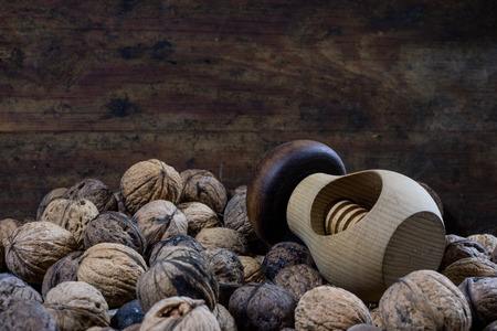 Walnuts on a wooden kitchen table. Nuts and a black wooden crate with a nutcracker. Black background.の写真素材