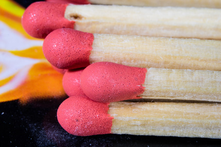 Matches enlarged. Several heads of matches with sulfur to set candles on. Dark background.