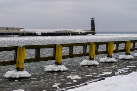 Lighthouse at the port wharf. The port is ice-covered. Winter season.の写真素材