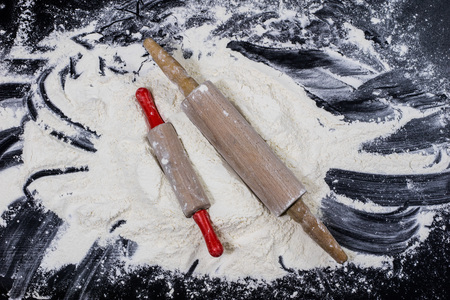 Flour and rolling pin for kneading the dough on the kitchen table. Accessories and kitchen products. Black table top.の写真素材