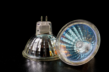 Halogen bulb in a reflective shade. Lighting accessories on a dark tole. Black background.の写真素材