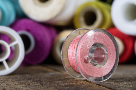 Threads and needle on the table in a tailor's workshop. Close-up sewing accessories. Dark...