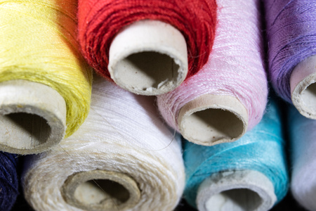 Threads and needle on the table in a tailor's workshop. Close-up sewing accessories. Dark...