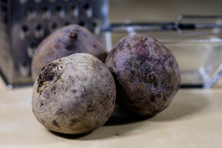 Beet grated on a kitchen grater. Kitchen countertop and preparation of salads. Dark background.