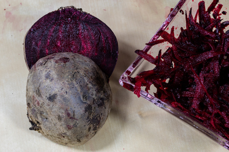 Beet grated on a kitchen grater. Kitchen countertop and preparation of salads. Dark background.の写真素材