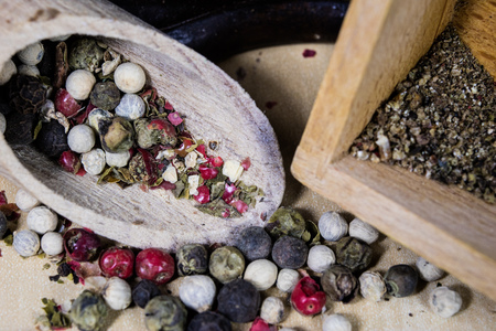 A grain of pepper on a kitchen table. Ground pepper in a kitchen mill. Culinary spices on a light...