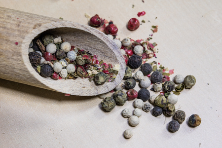 A grain of pepper on a kitchen table. Ground pepper in a kitchen mill. Culinary spices on a light...