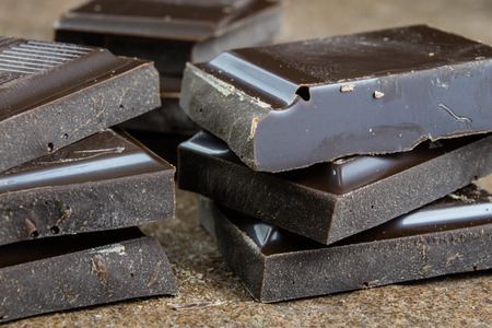 Black chocolate cubes broken and stacked on each other. Sweet dessert tastes best for coffee. Light...