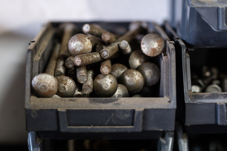 Metal screws in storage containers. Shelf locksmith workshop with parts for mechanical repairs. The interior of the production hall.の写真素材
