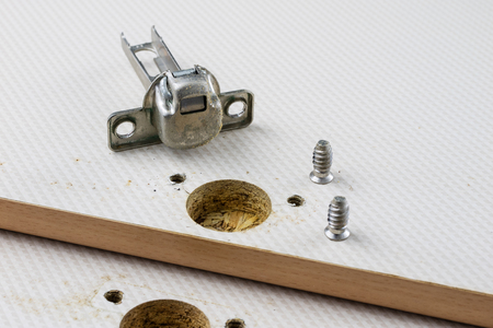 Assembly of hinges in a carpentry workshop. Joinery accessories in a carpentry workshop on a wooden table. Light background.の写真素材