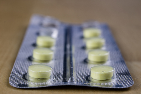 Pills in a wrapper on a wooden table. A medicine for a cold and a headache in a plastic package....