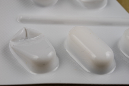 Pills in a wrapper on a wooden table. A medicine for a cold and a headache in a plastic package. Light background.の写真素材