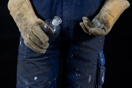 Hazardous materials and acids. Acid bottle kept in gloves by a construction worker. Dark background.の写真素材