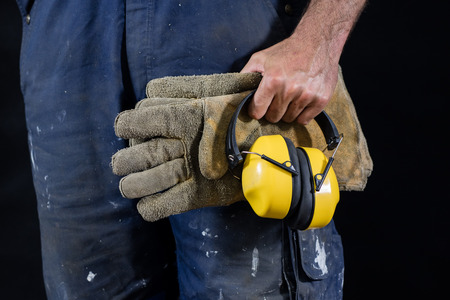 Helmet held by a construction worker. Protective clothing for manual workers. Dark background.の写真素材