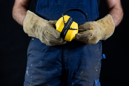 Helmet held by a construction worker. Protective clothing for manual workers. Dark background.の写真素材