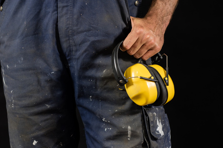 Helmet held by a construction worker. Protective clothing for manual workers. Dark background.の写真素材