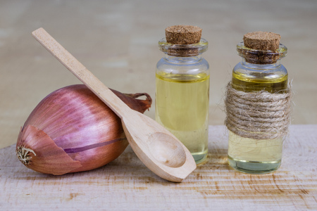 Syrup of onion in a small vial on a wooden table. Flu medicine in a small glass container. Light background.の写真素材