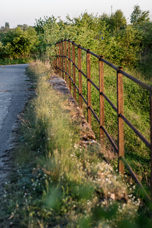 Steel handrail of the railway viaduct. Old rusty barrier on a brick railway bridge. Season of the spring.の写真素材