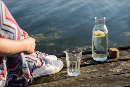 A bottle of water with lemon and a glass. Bridge over the lake and woman. Season of the spring.の写真素材