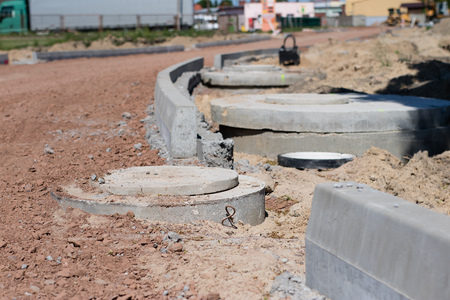 Construction site for a new road for cars. Laying paving blocks, new wells along the road. View of...
