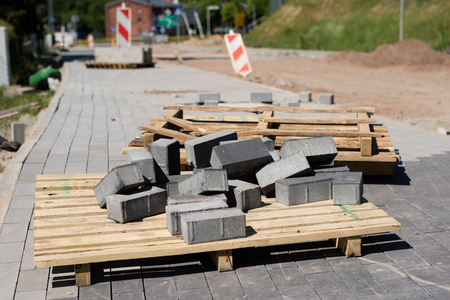 Construction site for a new road for cars. Laying paving blocks, new wells along the road. View of the construction site.の写真素材