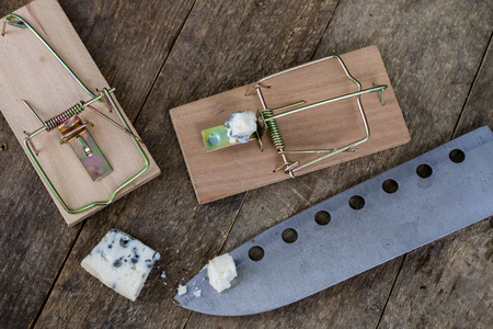 Mousetrap on an old wooden table. Metal accessories for extermination of small rodents. Dark...