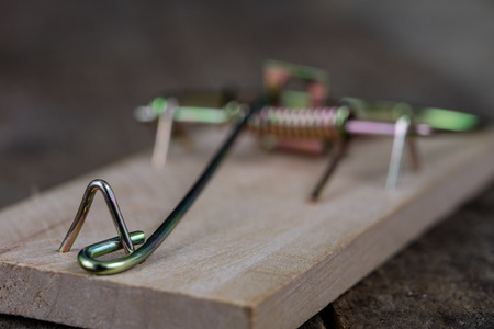 Mousetrap on an old wooden table. Metal accessories for extermination of small rodents. Dark background.の写真素材