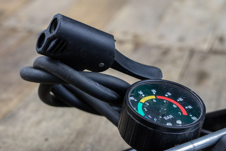 Foot pump and bicycle tube on a wooden workbench. Accessories for bicycle and car tires repair. Dark background.の写真素材