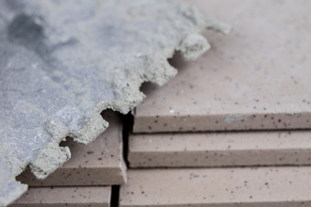 Tiles for laying on the floor. Accessories and material for a construction worker arranged on a wooden workshop table. Dark backgroundの写真素材