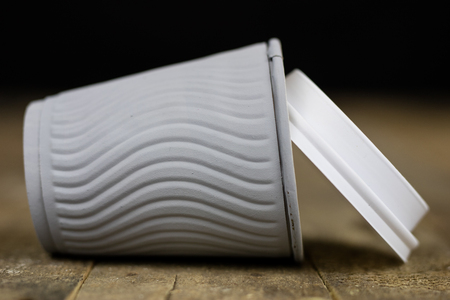 Coffee mugs in a paper mold on a wooden table. Disposable dishes used in the fast-food bar. Dark background.の写真素材