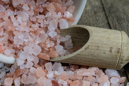 Rock salt and wooden spoon on an old wooden kitchen table. Spices in the old kitchen. Dark...