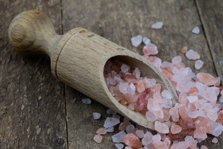 Rock salt and wooden spoon on an old wooden kitchen table. Spices in the old kitchen. Dark background.の写真素材