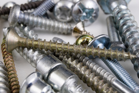 Screws on a white table. Accessories for screw connections. Light background.