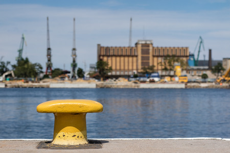 Harbor bollard for large naval vessels. The port wharf in central europe. Season of the summer.