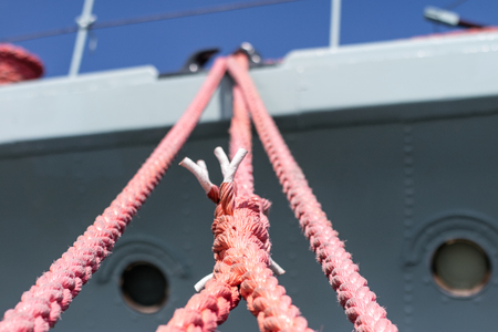 Ship mooring rope on the port wharf. Harbor bollard for large naval vessels. Season of the summer.