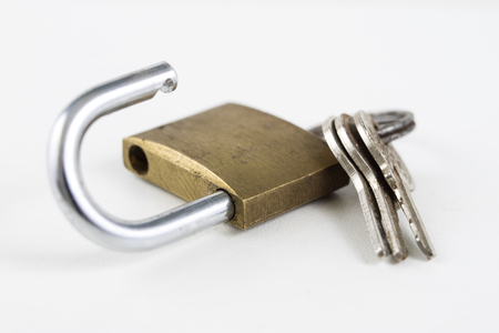 Brass padlock on a white table. Accessories for locking and securing against burglary. White background.の写真素材
