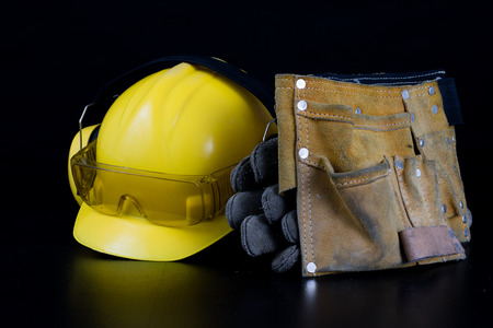 Helmet and workwear on a black working table. Accessories for construction workers. Black background.の写真素材