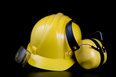 Helmet and workwear on a black working table. Accessories for construction workers. Black background.の写真素材