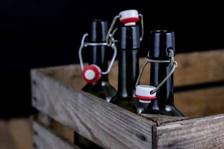 Old bottles in a wooden case. Drinks in old glass containers. Dark background.の写真素材