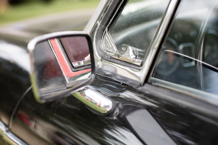Chrome mirror in an old car. Accessories in cars exhibited at shows. Season of the summer.